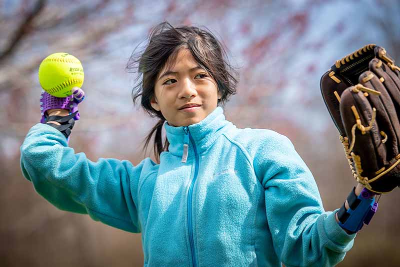 Tori throwing a softball with her new prosthetic hands.