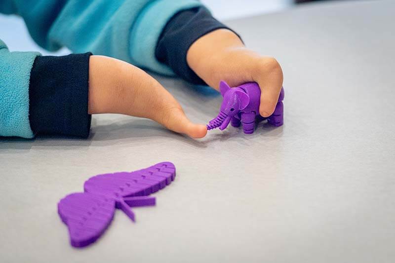 Tori Anderson plays with an elephant made on the same 3D printer as her prosthetic hands.