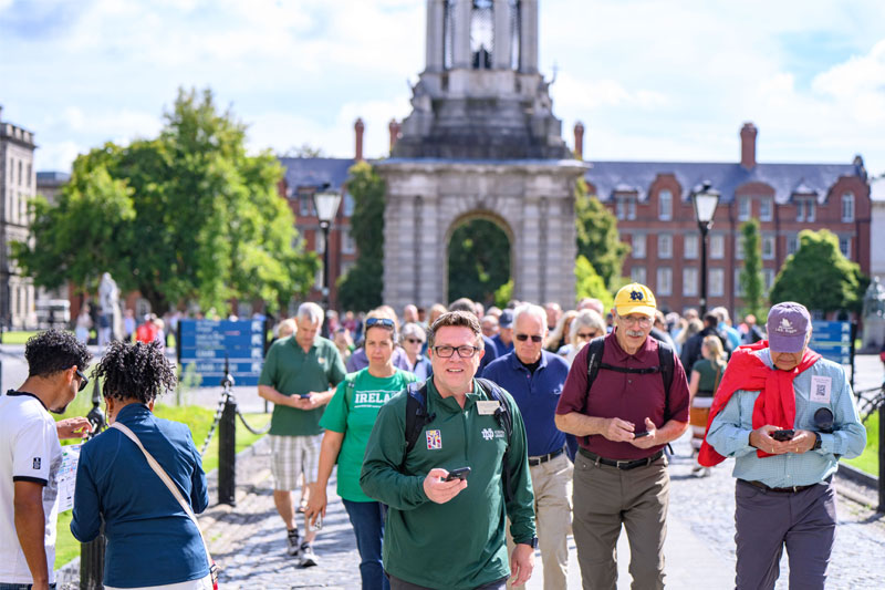 A group of people do a walking tour outside Trinity College in Dublin.