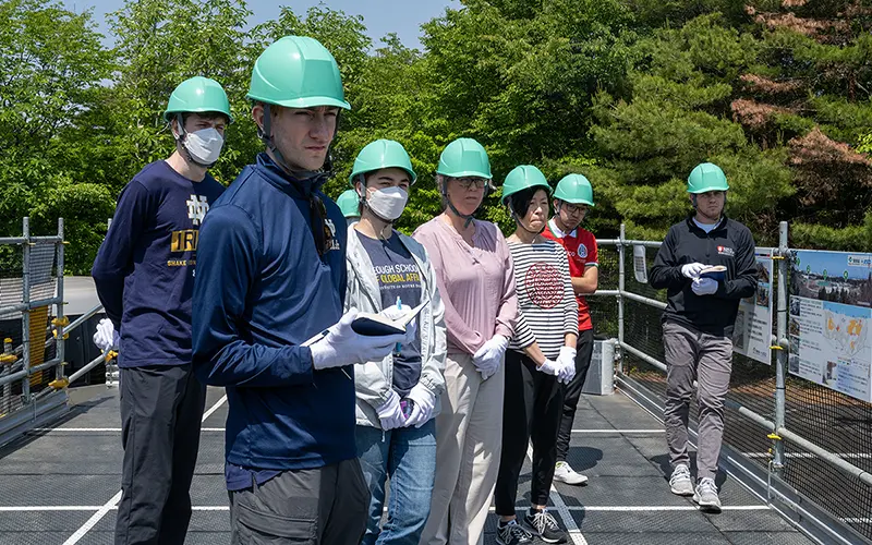 While wearing hardhats, the Notre Dame team listens as a TEPCO representative explains the layout of the nuclear plant and the events that led to the meltdown.