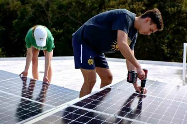 A male and female student work on installing solar panels
