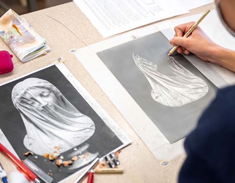 Erasing on a dark background to sketch a statue of a woman's face covered with a cloth.