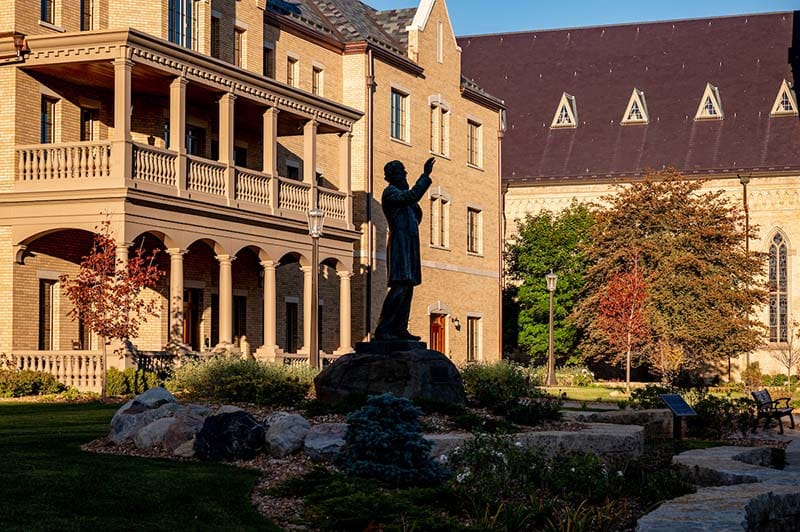 A statue of Fr. Corby in front of Corby Hall on a fall day.