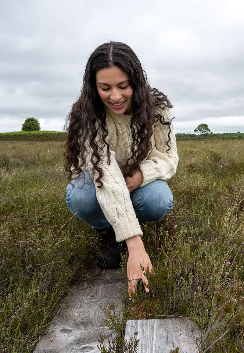 Mariana Silva bending down and touching vegetation
