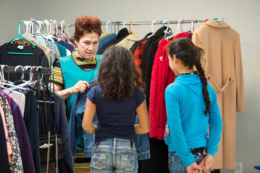 A member of Catholic Charities of the Rio Grande Valley helps two girls pick out new clothes.