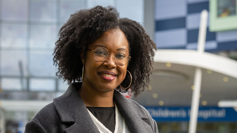 A portrait of Mackenzie Isaac in front of a hospital.