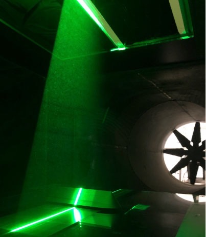 A green laser reveals the Toumba model inside a wind tunnel. You can see the wind tunnel fan in the background.