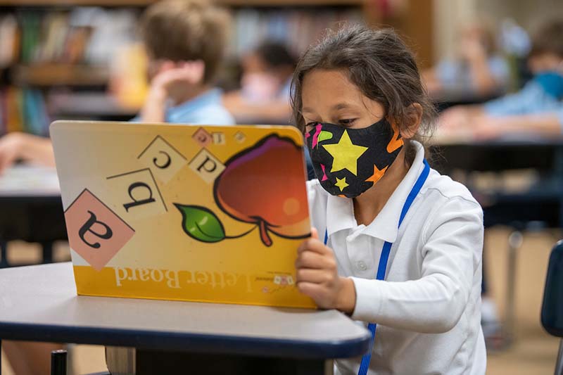 A masked student looks at a lettering book.