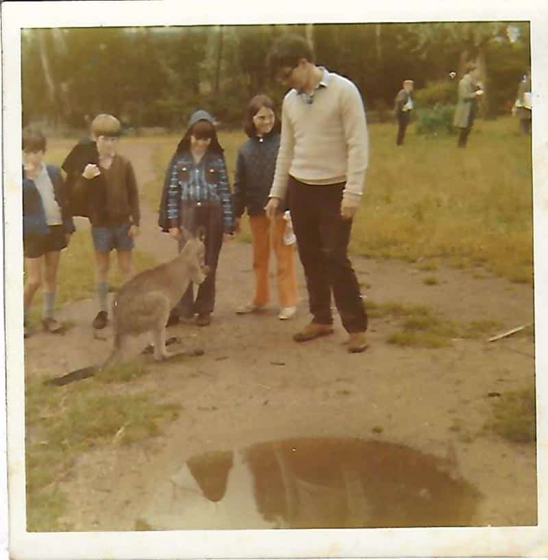 One adult and four kids stand around a kangaroo.