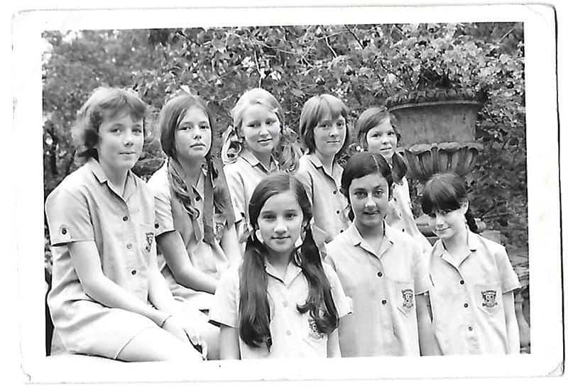 A group of girls pose for a photo wearing school uniforms.