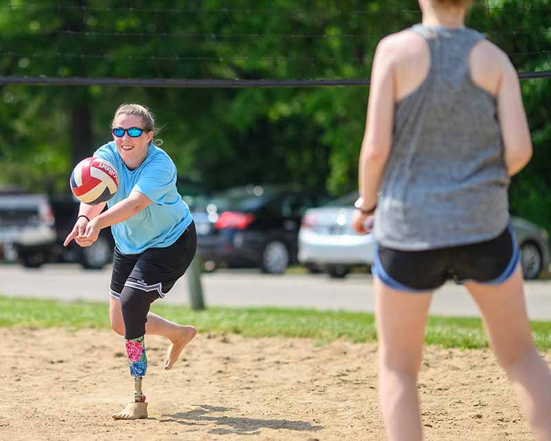 A woman plays volleyball while wearing a prosthetic lower-leg.