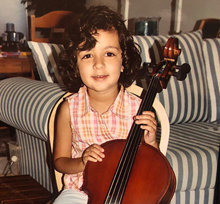 A childhood photo of a young girl holding a cello.