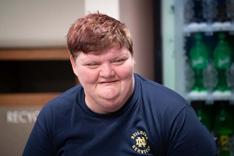 A woman smiles, wearing a navy Building Services shirt.