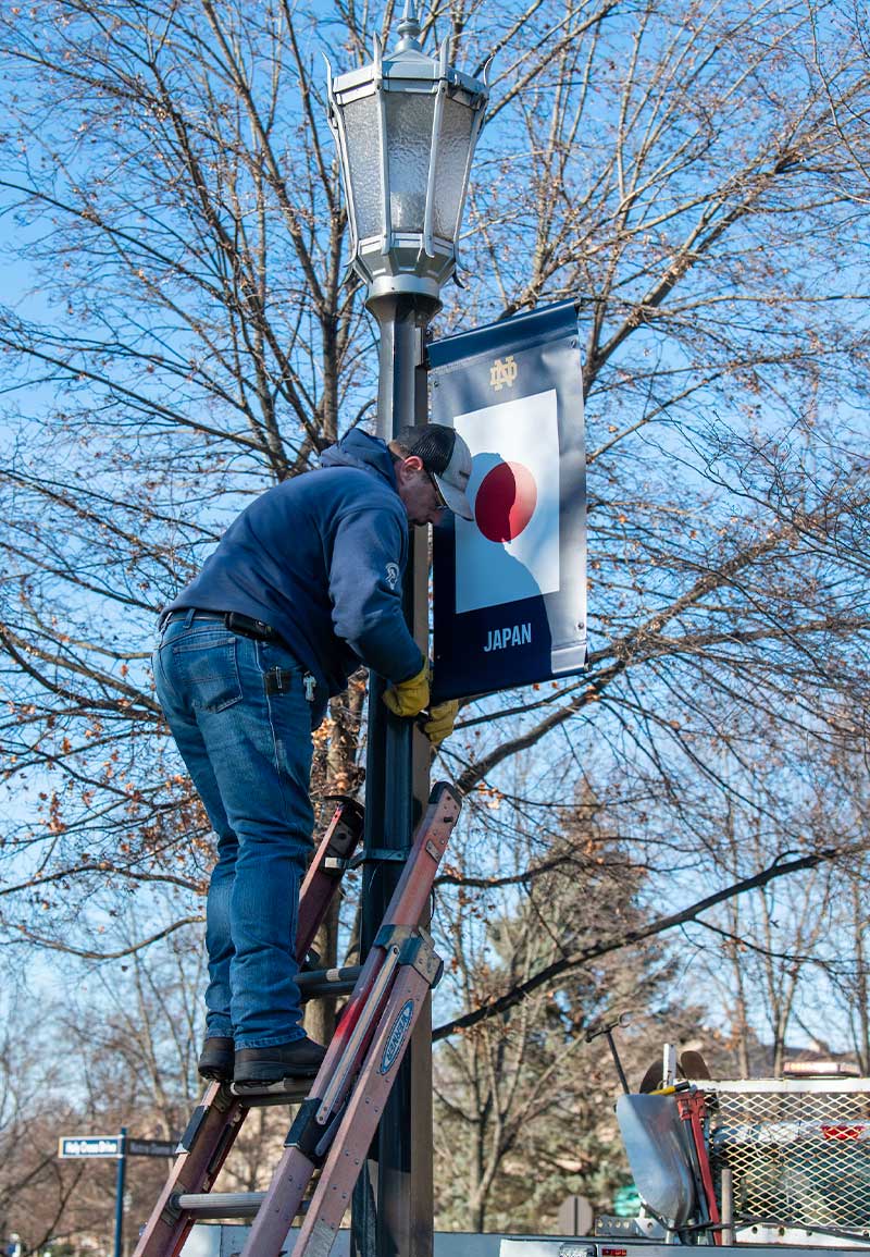 A man installs a banner representing Japan's flag on a lamp post.