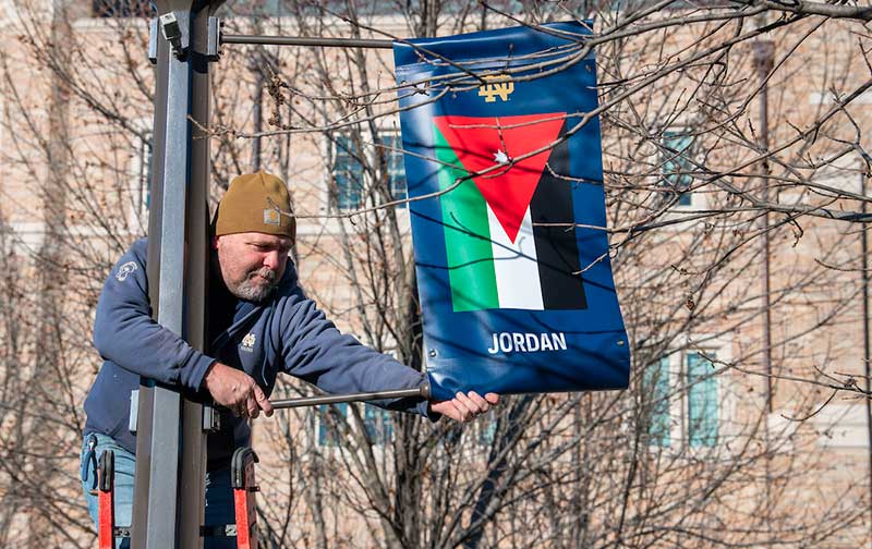 A man installs a banner representing Jordan’s flag on a lamp post.