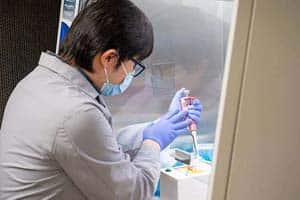 A man in a labcoat works on a COVID-19 test device.