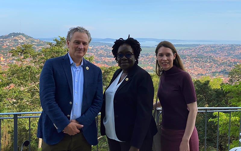 Pippenger and guests standing on a balcony with the city of Kampala in the background.