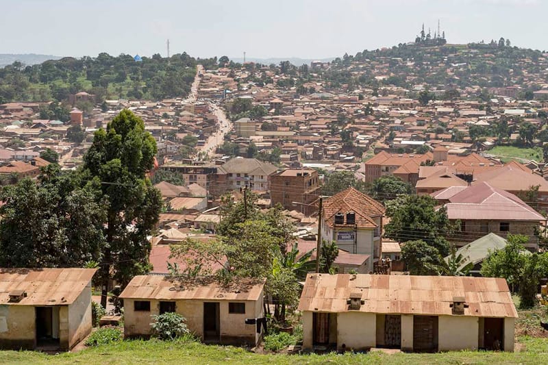 An aerial view of a Ugandan town with many homes with terra cotta and metal roofs.