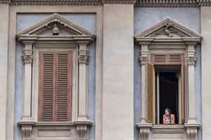 A woman looks outside her balcony window.