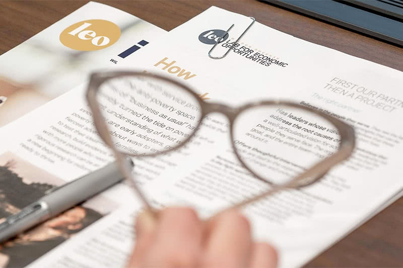 Papers on a desk with some words in focus looking through the lense of a pair of reading glasses.