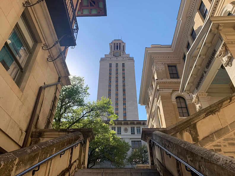 View of the tower on campus of University of Texas as looking up from a set of stairs.