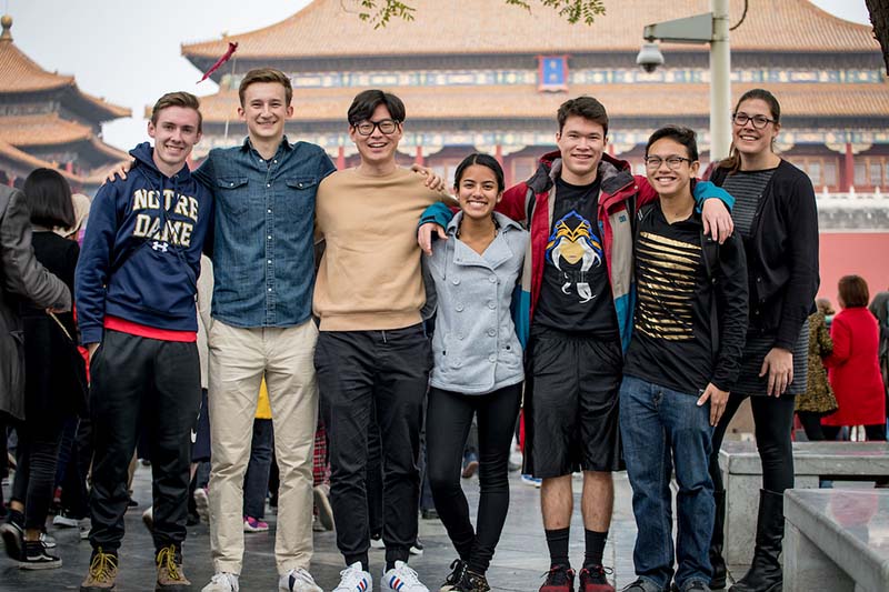 A group of 7 students pose together in front of Chinese building.