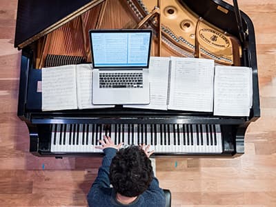 A student is pictured from above playing the piano