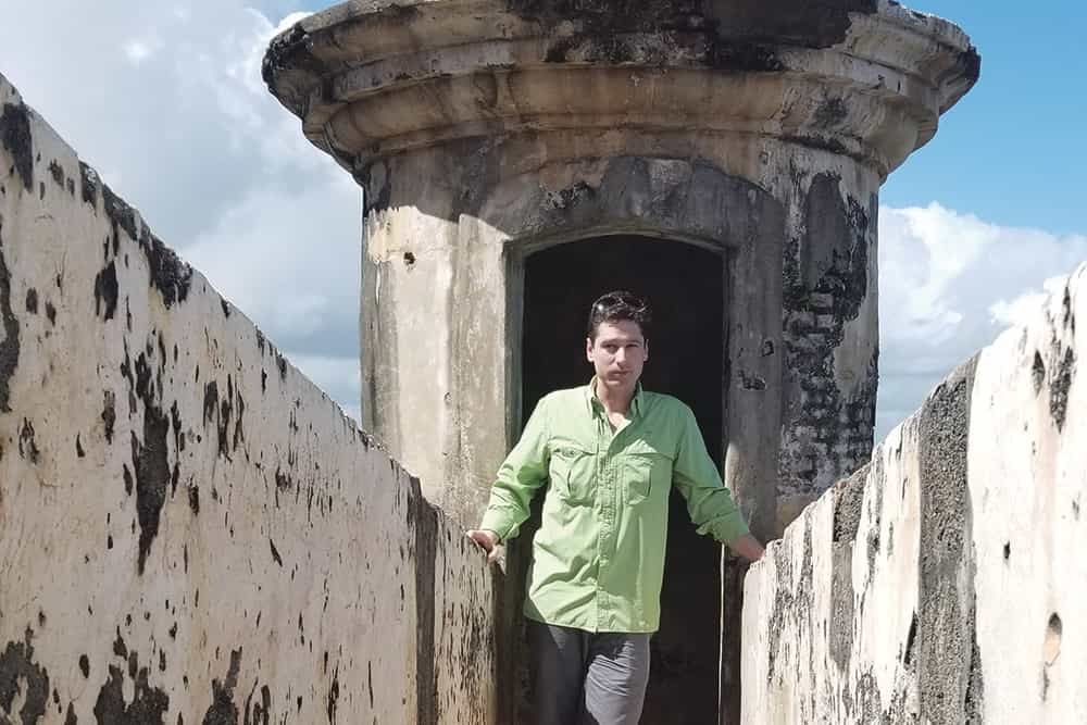 An individual poses on a deteriorated building.