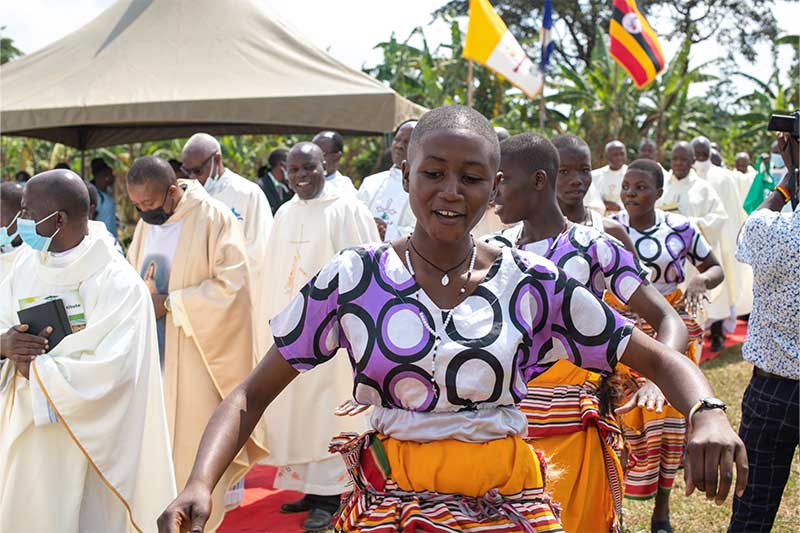 During a ceremony, women wearing colorful traditional clothing sing and dance.