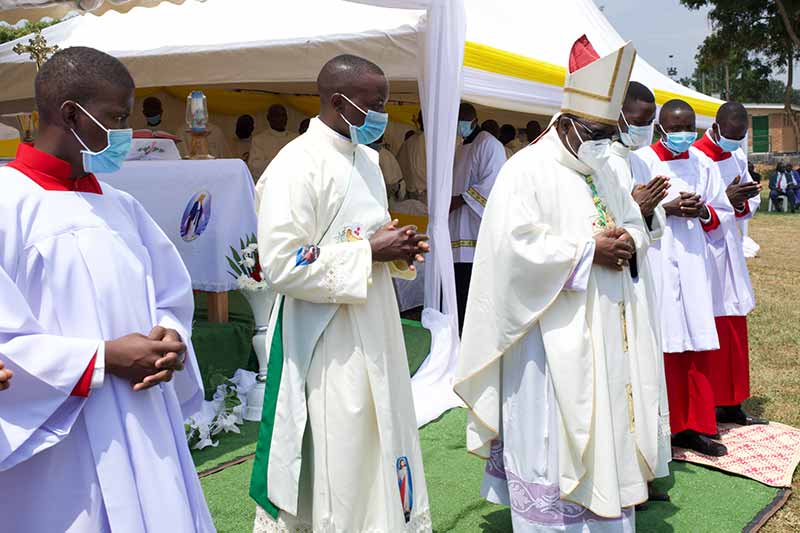 An Archbishop and others bow their head during Mass.