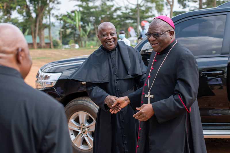 Archbishop Paul Ssemogerere is greeted by government officials.