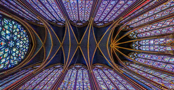 A straight up view of the ceiling of Saint-Chapelle showing intricate symmetry of lines and structures.