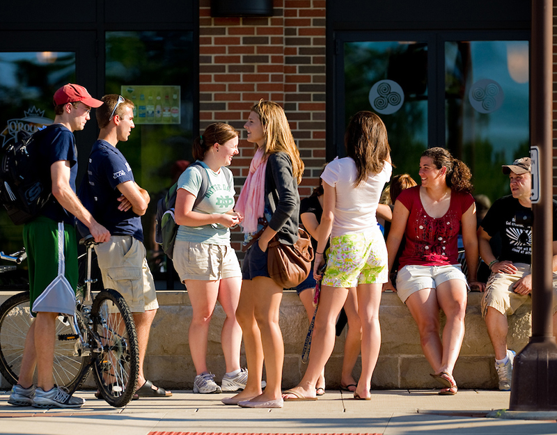 A group of presumed Notre Dame students, three male and four female, chat outside a storefront on Eddy Street.