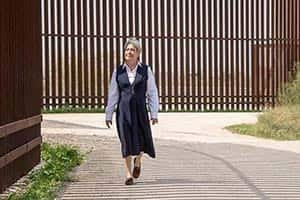 Sister Norma walks beside the border wall.