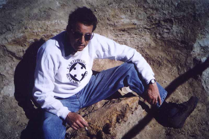 A man sitting on the ground wearing sunglasses.