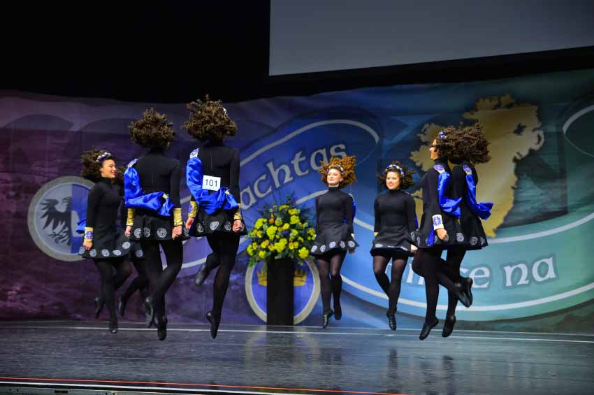 Dancers in black dress jumping in unison on stage
