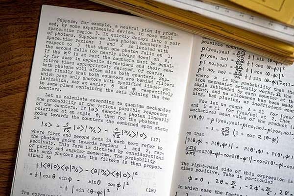 Physics article and equations open in a journal on a table in the library.