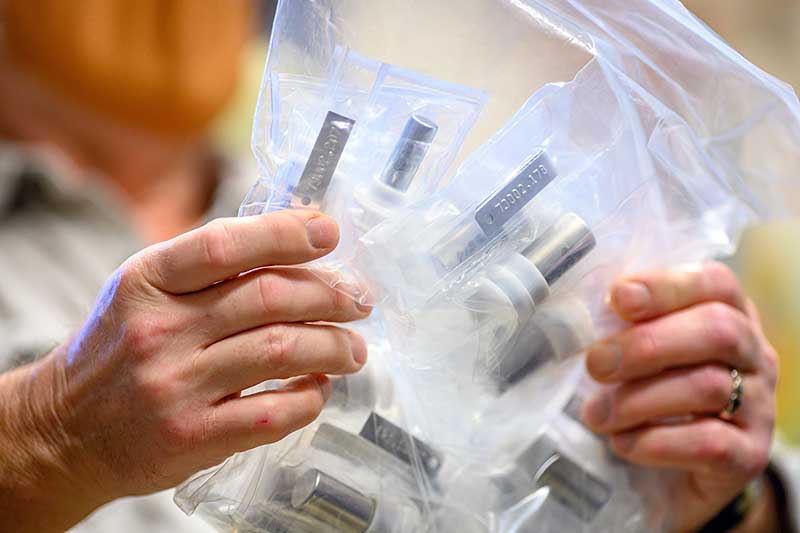 A close up shot of a man's hands holding bags of canisters of lunar dust.