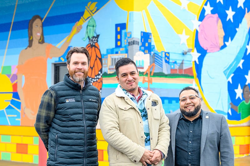 Three men standing in front of a painted wall mural.