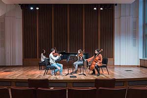 A group of four student musicians perform together on a stage.