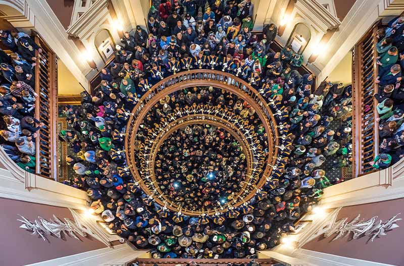The Notre Dame Marching Band trumpet players perform in the Main Building rotunda surrounded by fans.