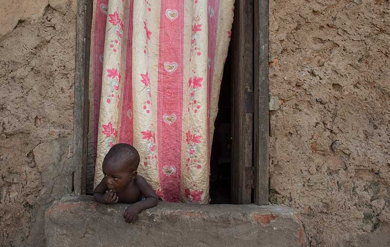 A child looks out the front window of the house where Alex Kawooya was born and lived until he was 11 years-old in Kalerowa slum in Uganda.