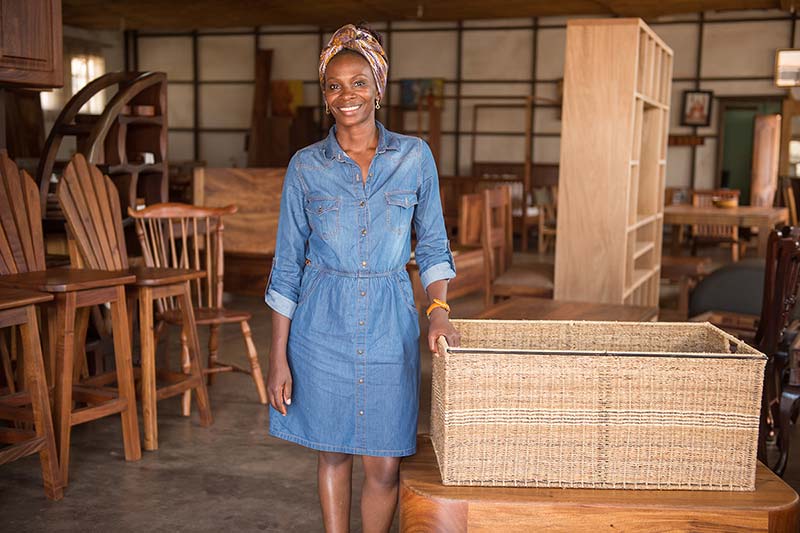 Evelyn Zalwango stands next to a basket made that out of banana fibers.