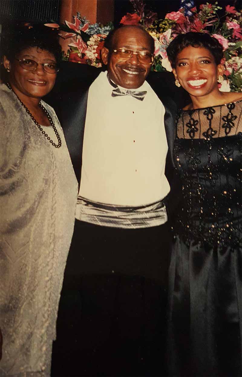 A mother, father, and daughter dressed up at an event pose for a photo dressed.