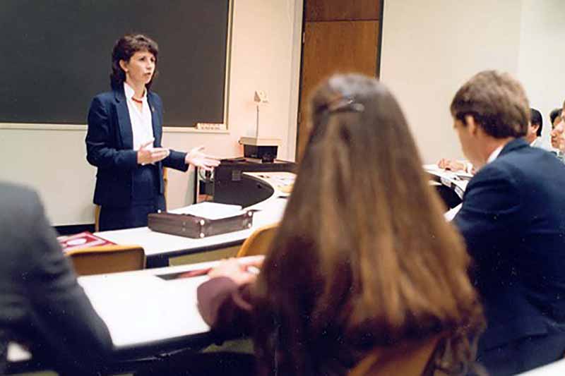 An archival photo of Kathleen McChesney in front of a classroom.