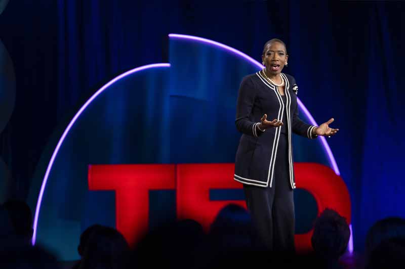A woman speaks on a TED Talk stage.