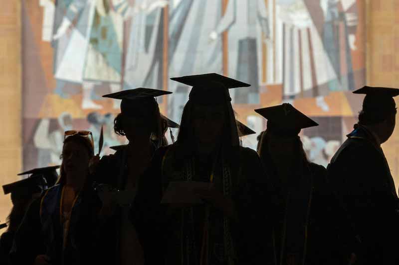A silhouette of a group of graduates.