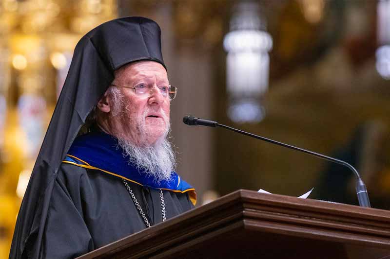 Patriarch Bartholomew stands at a podium.