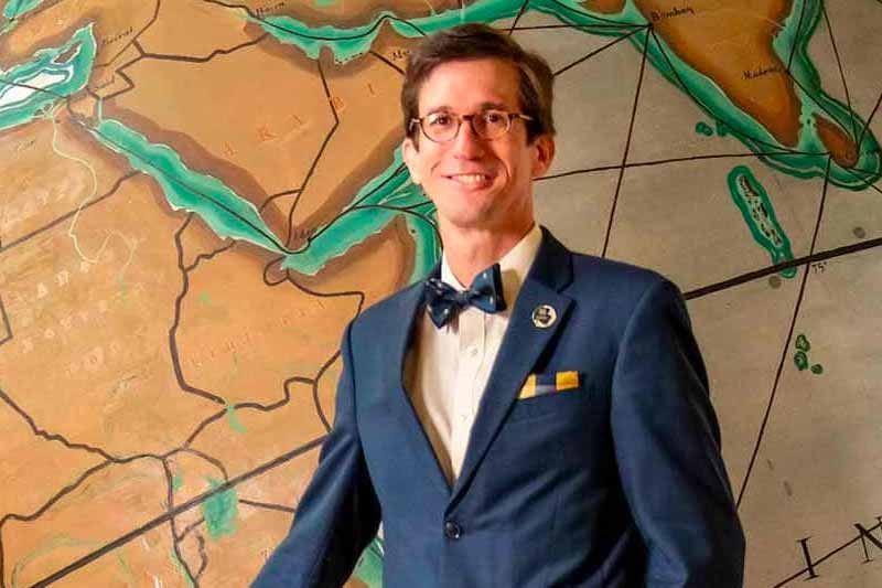 A portrait of Santiago Schnell in front of a globe.