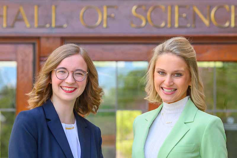 A portrait of two women, Madeline Owen and Alexis Waldschmidt, outside of Jordan Hall of Science.